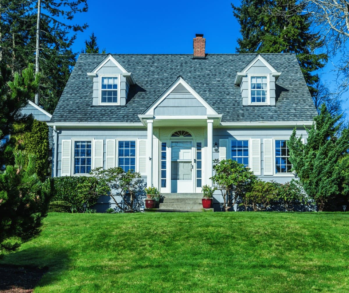 Cape-style house with dormers above a green lawn