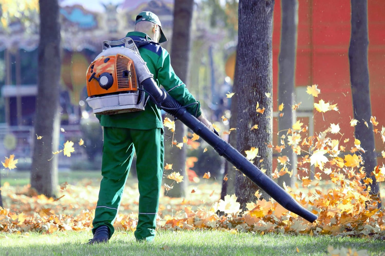 Worker clearing autumn leaves with a backpack leaf blower