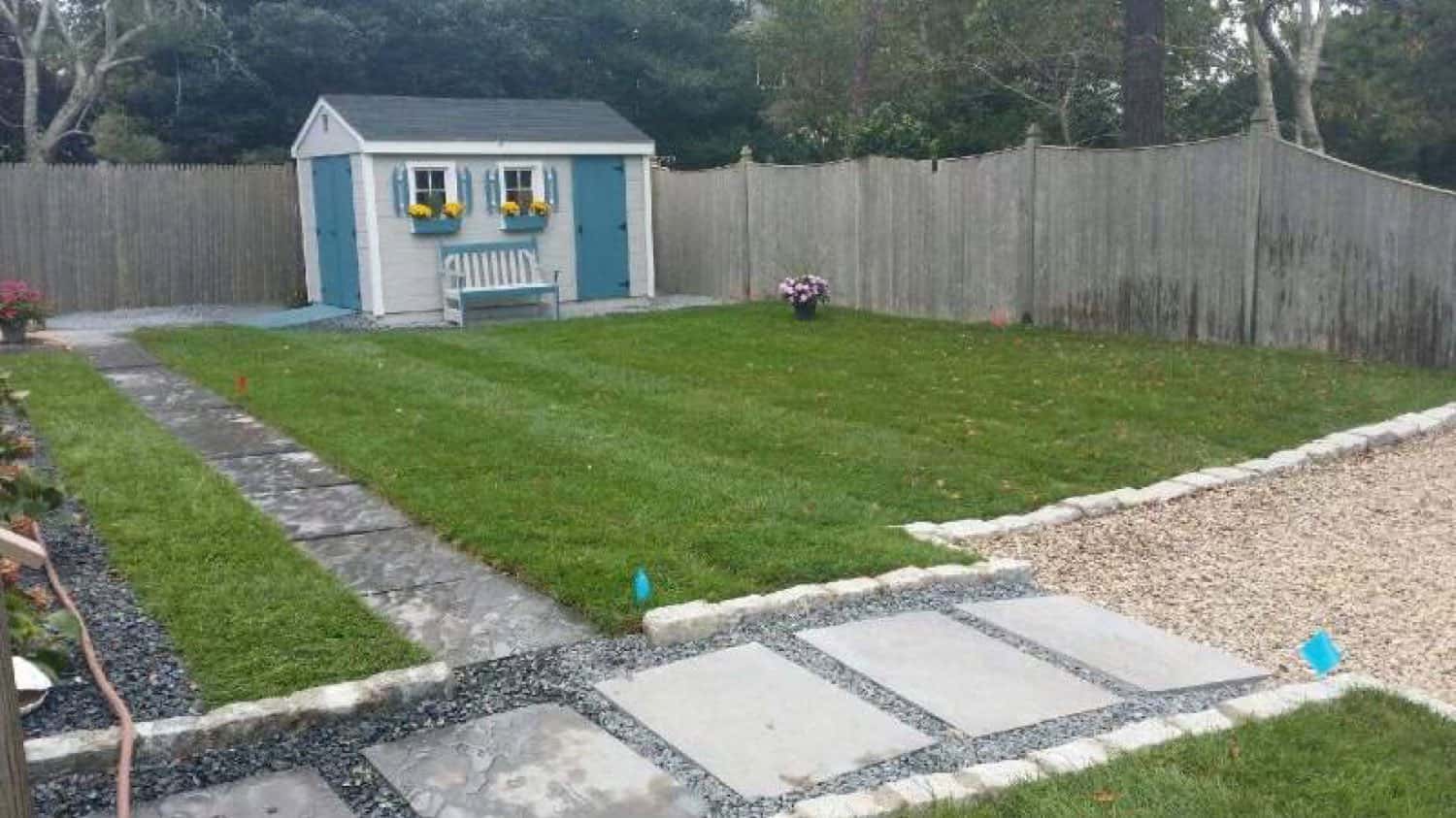 Backyard with a new lawn, stone walkway, gravel border and garden shed
