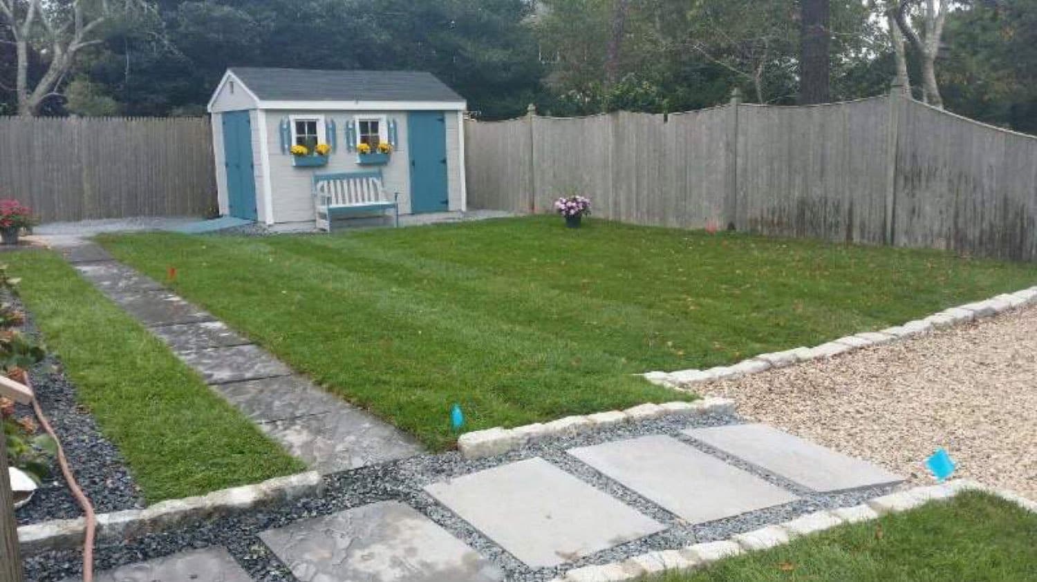 Backyard with a new lawn, stone walkway, gravel border and garden shed