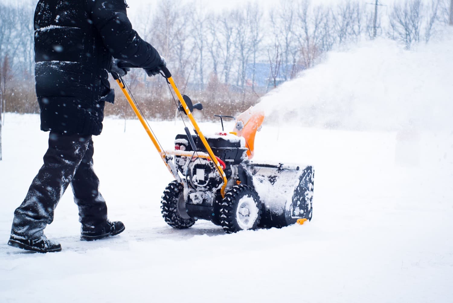Person clearing a path with a two-stage snow blower as snow falls